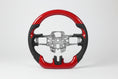 A red and black carbon fiber steering wheel with Nappa leather grips and metal interior structure, designed for a Ford Mustang.