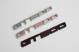 Three 'GT500' emblems in different colors on a white background