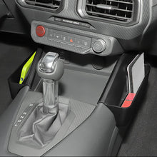 Close-up of a car center console with a manual gear shift stick, dashboard vents, climate controls, and side storage compartments.