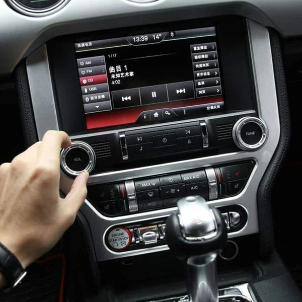 Car dashboard with a hand adjusting the radio, displaying a music player interface.